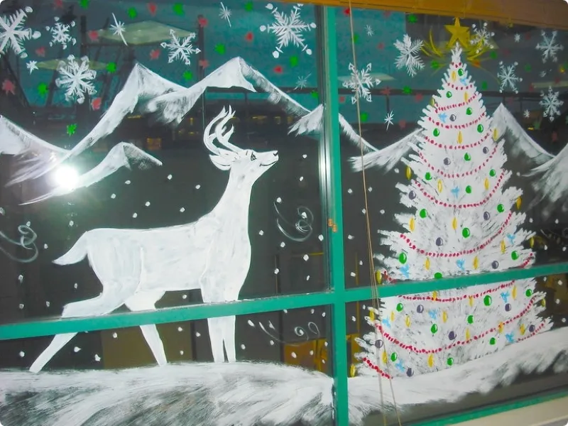 На стеклянной стене нарисована елка, олень и горы